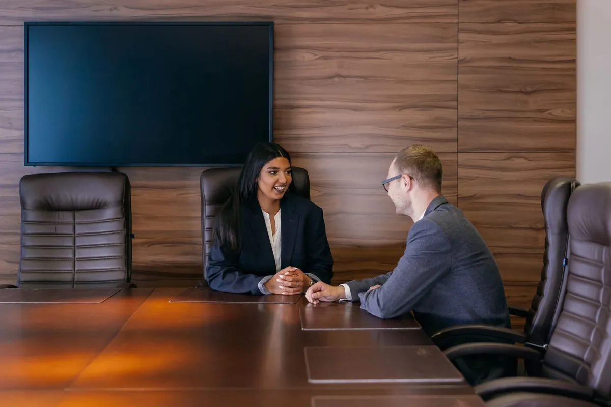 Two people in discussion across a boardroom table