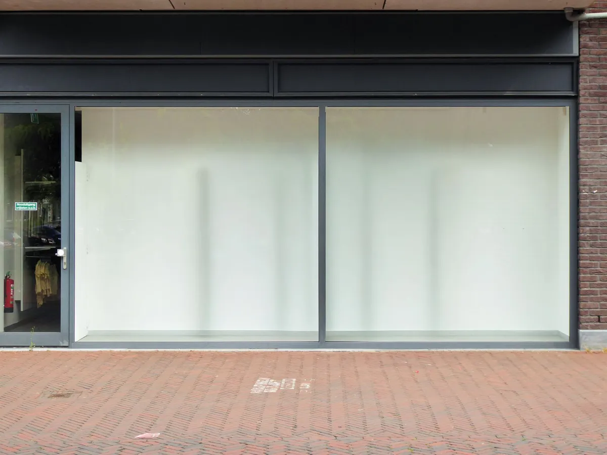 An empty shop unit with whitewashed windows on a brick high street