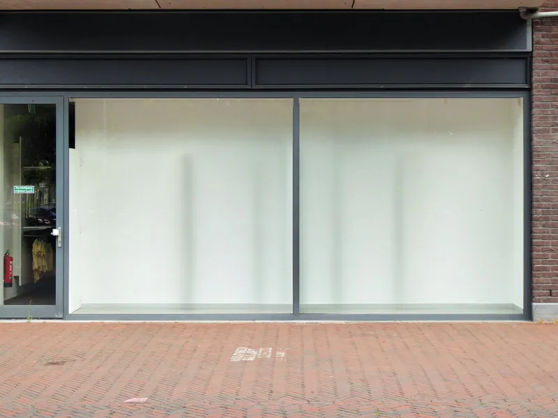 An empty shop unit with whitewashed windows on a brick high street